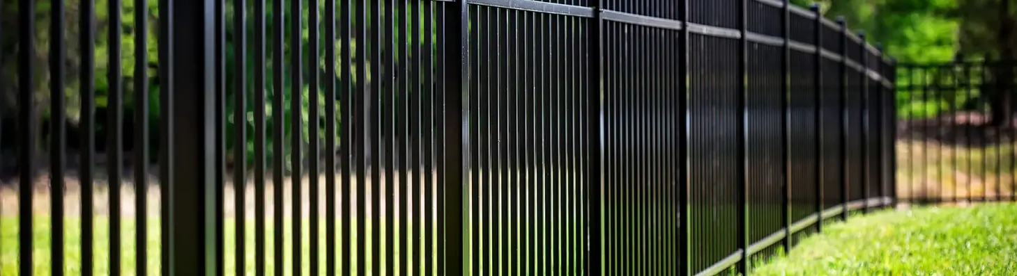 Black aluminum picket fence along a lawn