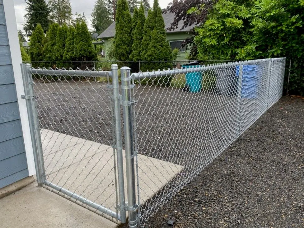 Galvanized chain-link fence with a walk gate beside a house