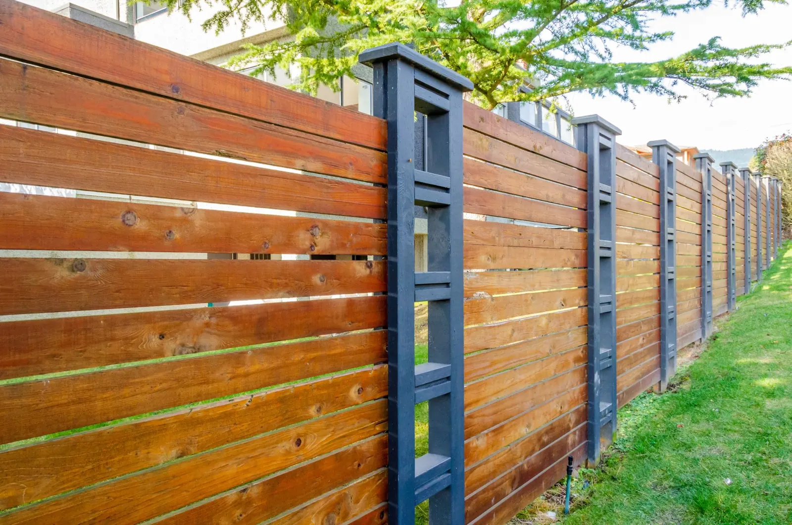 Horizontal wood slat fence with dark blue painted posts