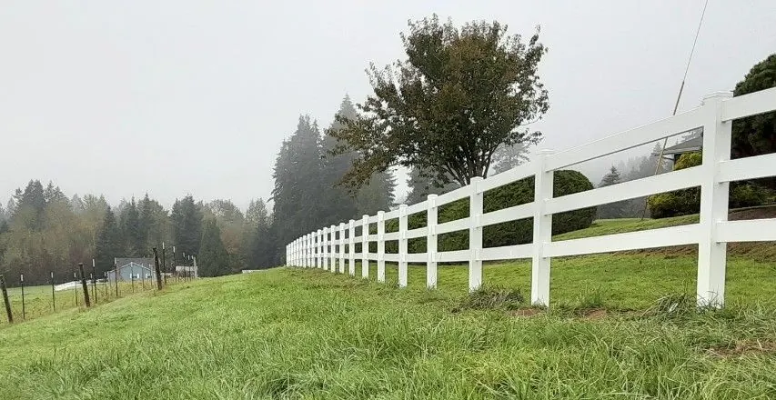 White vinyl rail fence along a field